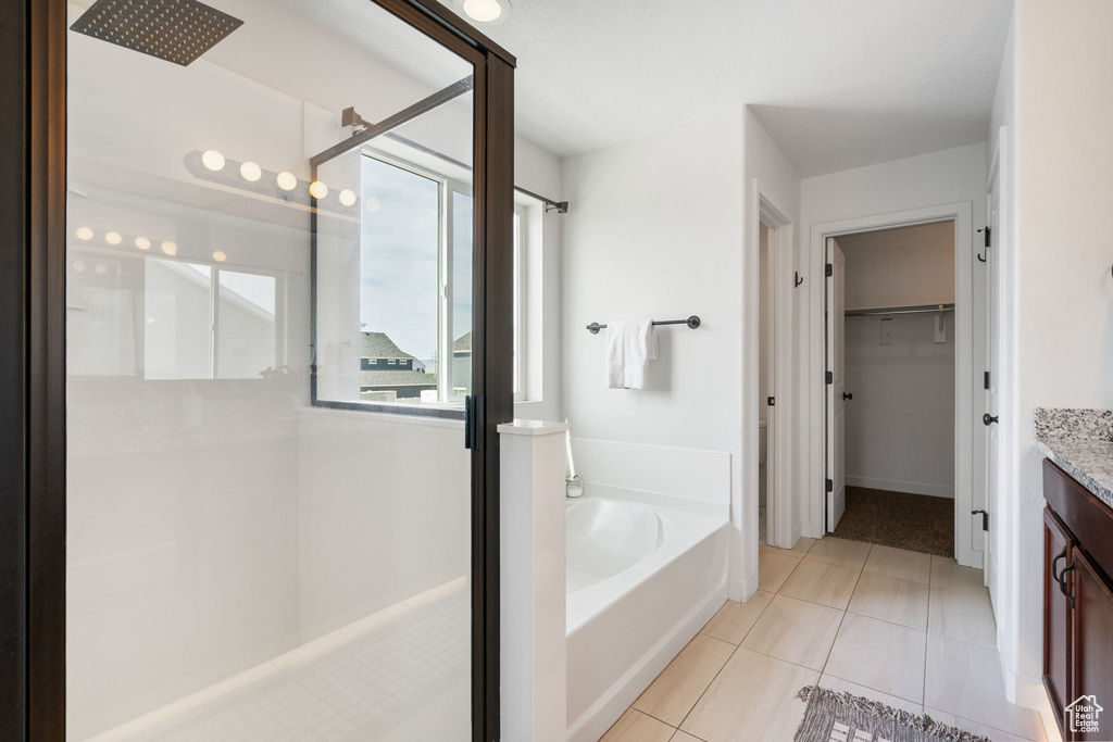 Bathroom featuring a stall shower, vanity, a bath, a walk in closet, and tile patterned floors
