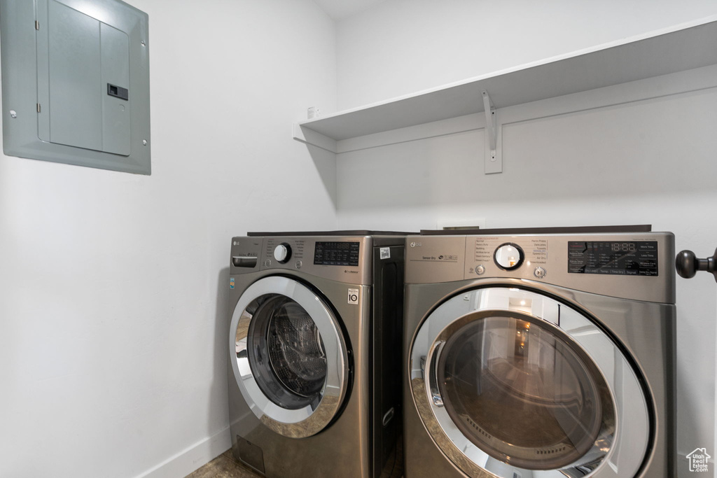 Laundry area with electric panel, washing machine and dryer, and baseboards