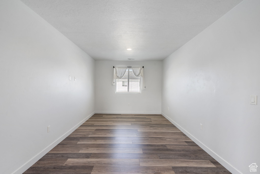 Spare room with baseboards, wood finished floors, and a textured ceiling