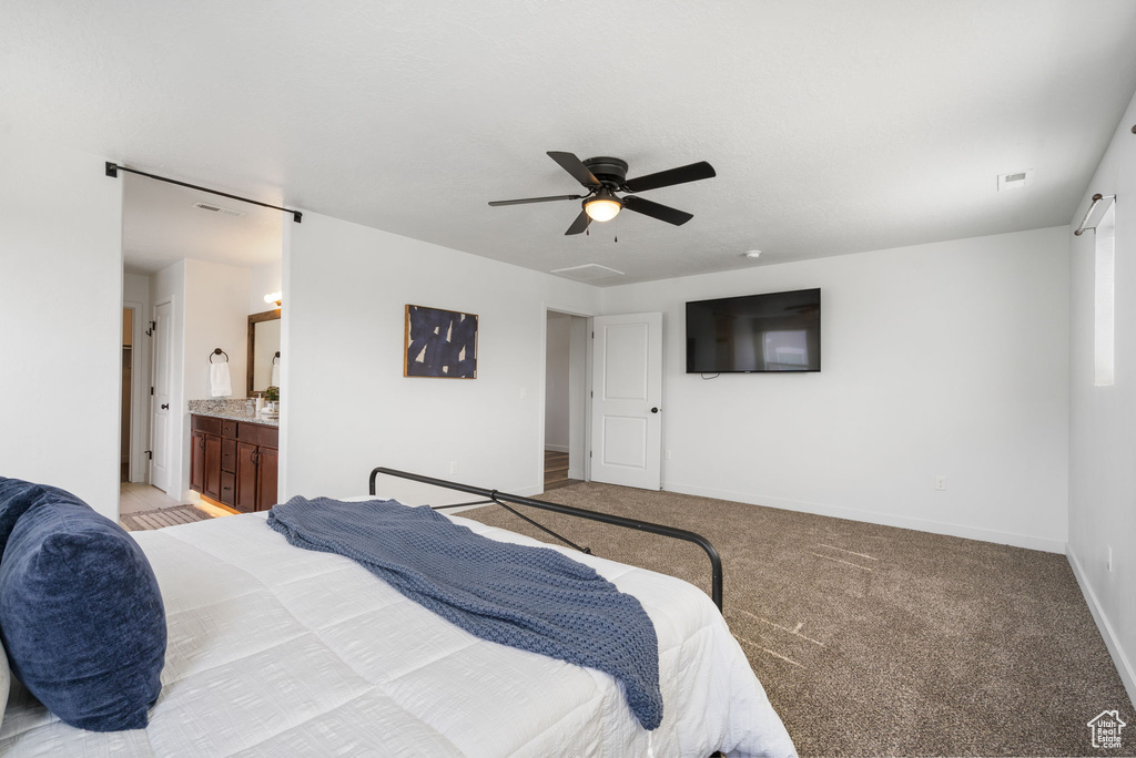 Bedroom with light colored carpet, baseboards, ceiling fan, and connected bathroom