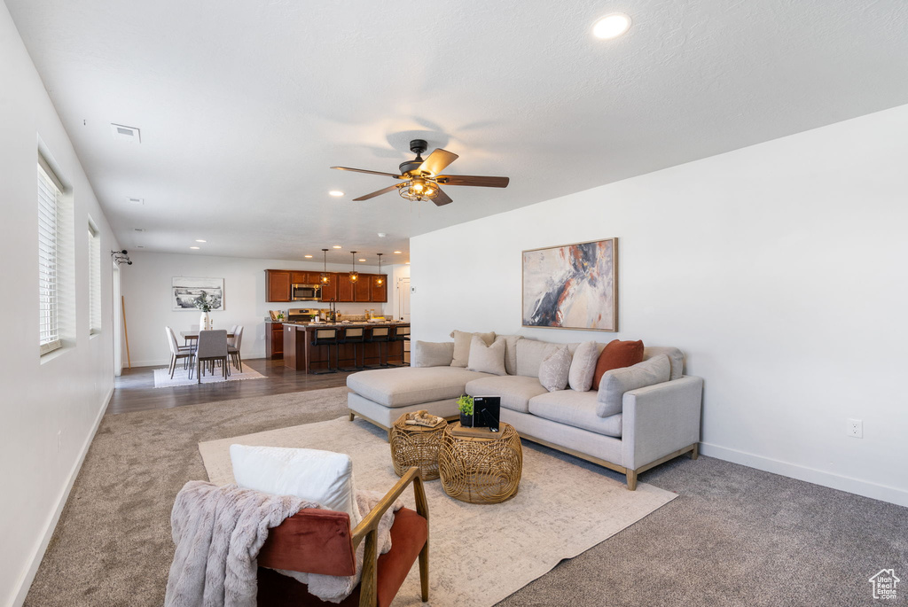 Living area with baseboards, a ceiling fan, recessed lighting, and light carpet