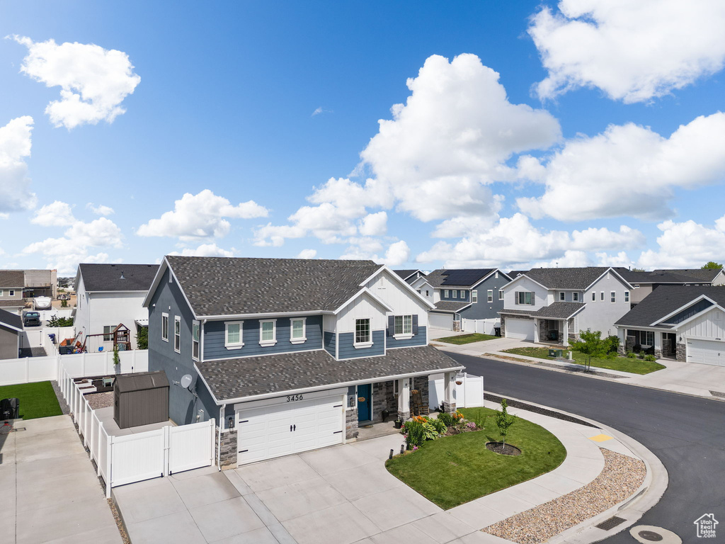View of front of house featuring a residential view, a garage, a gate, stone siding, and concrete driveway
