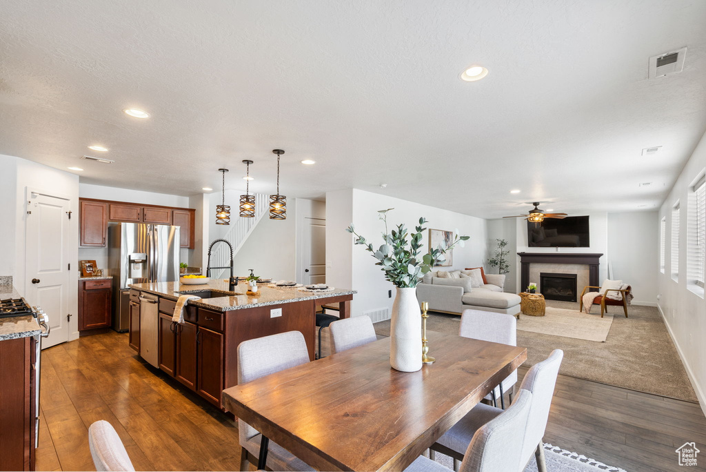 Dining area with a ceiling fan, dark wood-style floors, recessed lighting, a glass covered fireplace, and baseboards
