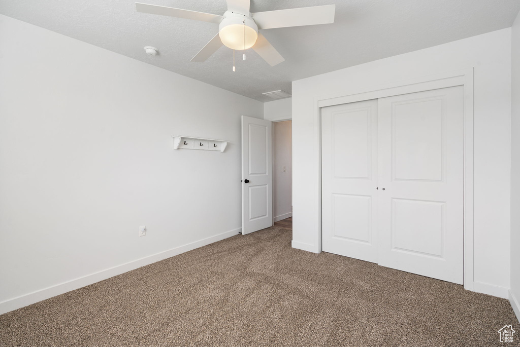 Unfurnished bedroom with carpet floors, a closet, baseboards, and a ceiling fan