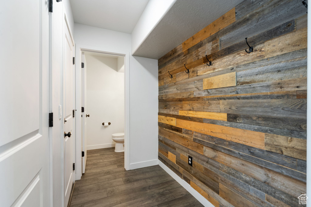 Corridor with wooden walls, dark wood-style flooring, and baseboards