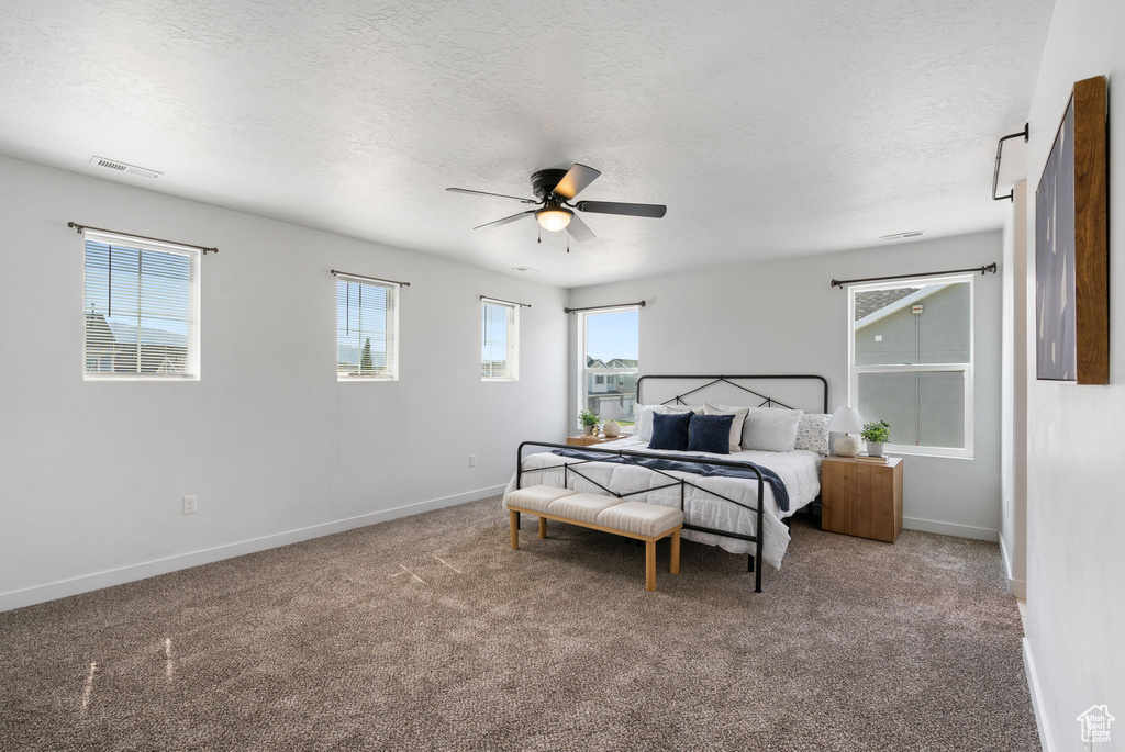 Carpeted bedroom with baseboards, a textured ceiling, and a ceiling fan