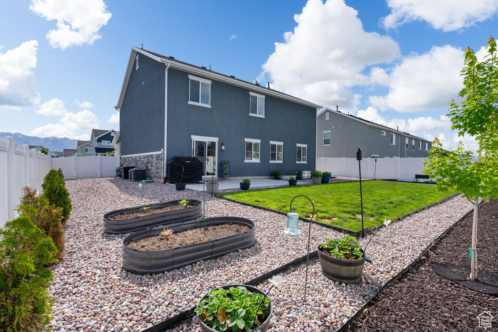 Back of property with a patio area, stucco siding, a garden, central air condition unit, and stone siding