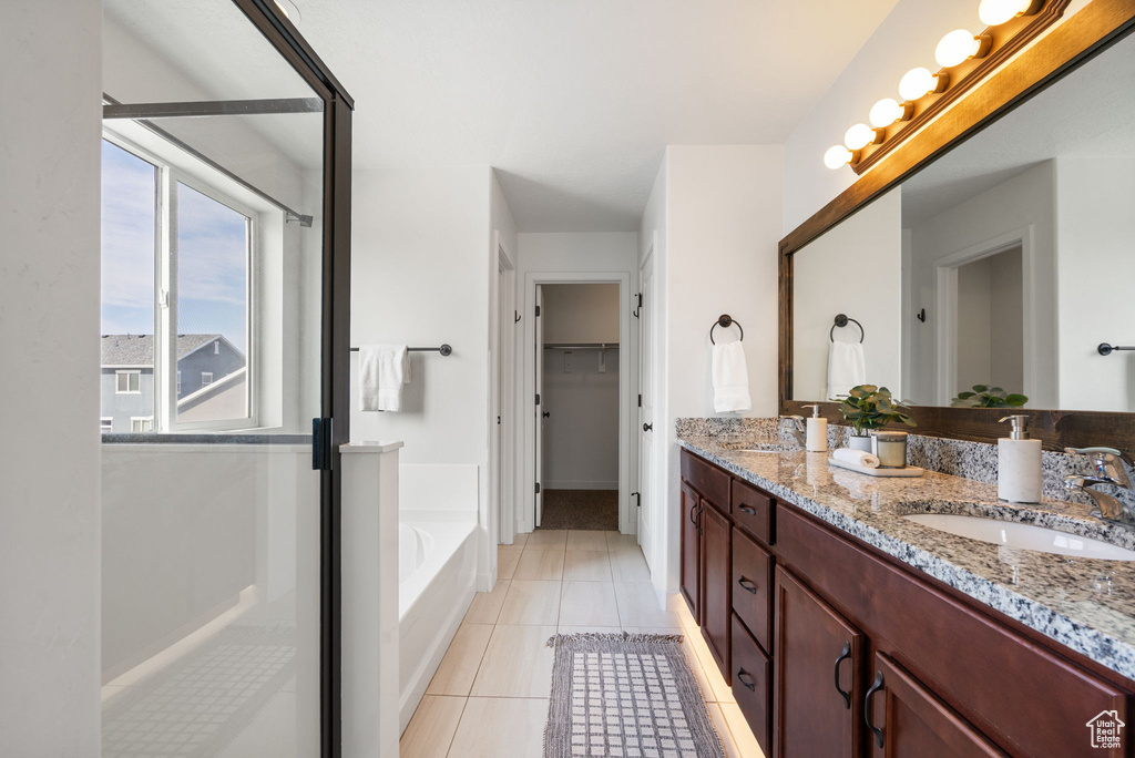 Bathroom featuring double vanity, a bath, tile patterned flooring, and a spacious closet