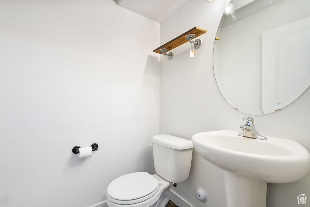 Half bathroom featuring baseboards, toilet, and a sink