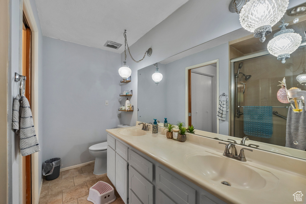 Full bathroom with double vanity, a shower stall, toilet, baseboards, and stone finish floors