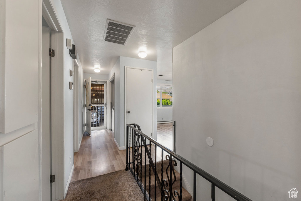 Corridor with an upstairs landing, light colored carpet, baseboards, and light wood-type flooring