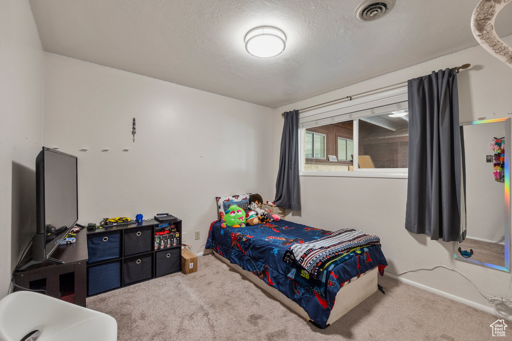 Carpeted bedroom with a textured ceiling and baseboards