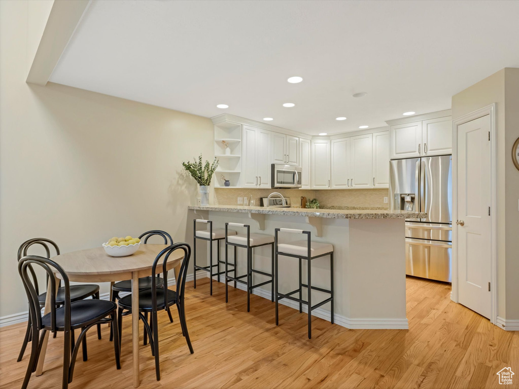 Dining room with light wood-type flooring, baseboards, and recessed lighting