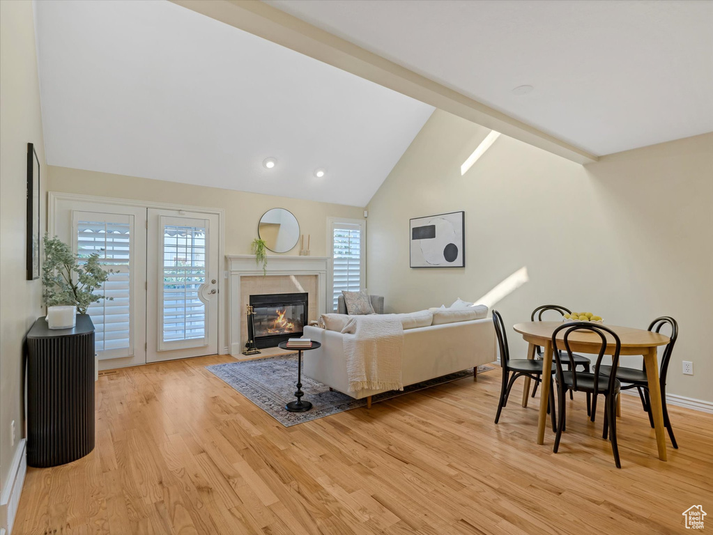 Living area with light wood finished floors, vaulted ceiling, a fireplace, baseboards, and a baseboard heating unit