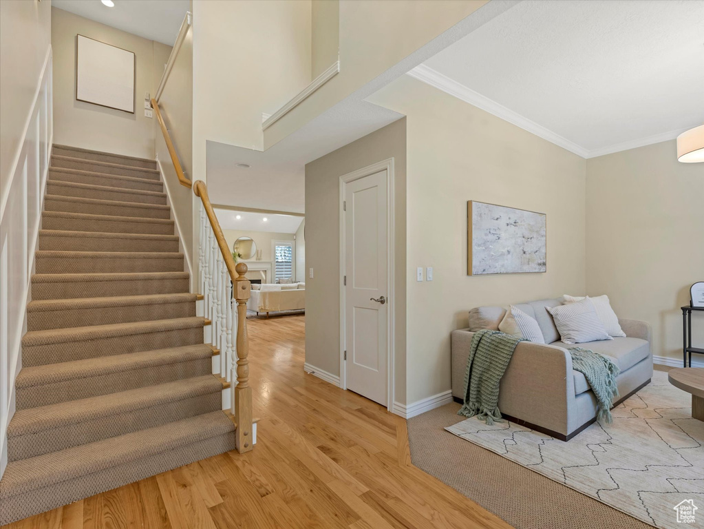 Stairway with wood finished floors, baseboards, ornamental molding, and recessed lighting