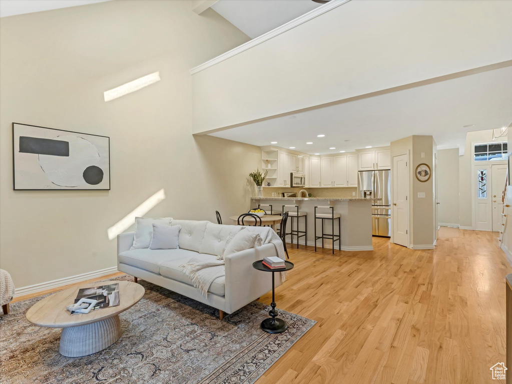 Living room with light wood finished floors, baseboards, and recessed lighting