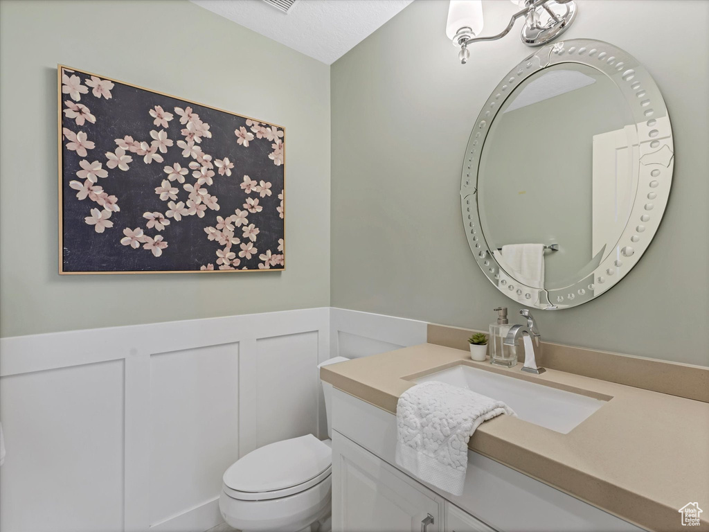 Bathroom with vanity, a wainscoted wall, a decorative wall, and toilet