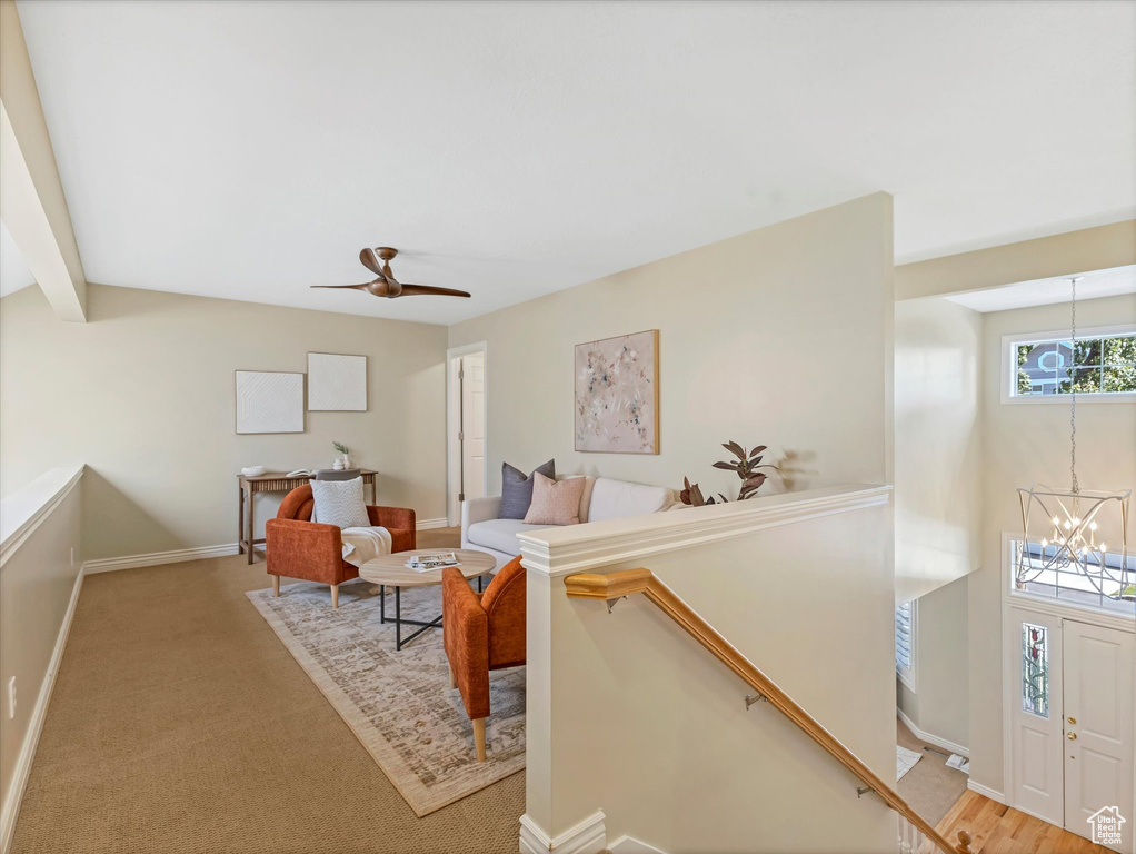 Carpeted living room featuring a chandelier, baseboards, and a ceiling fan