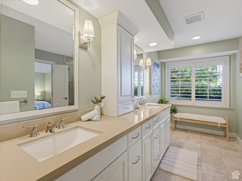 Ensuite bathroom with double vanity, recessed lighting, and baseboards