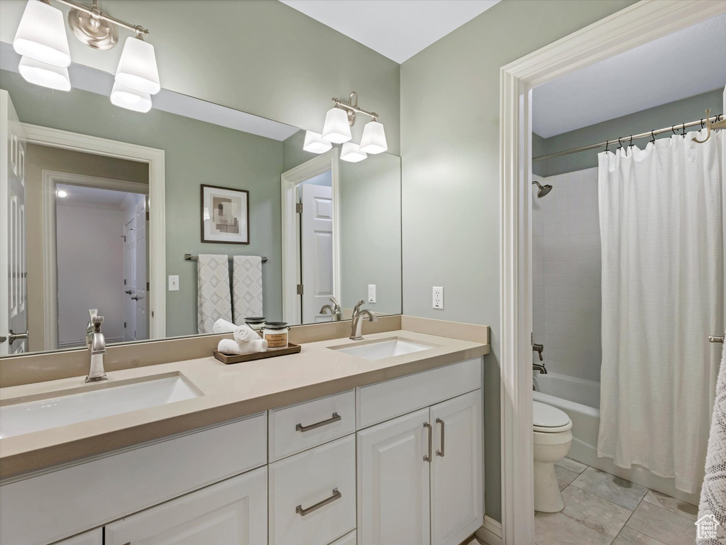 Full bath with double vanity, toilet, shower / bath combo, and tile patterned flooring