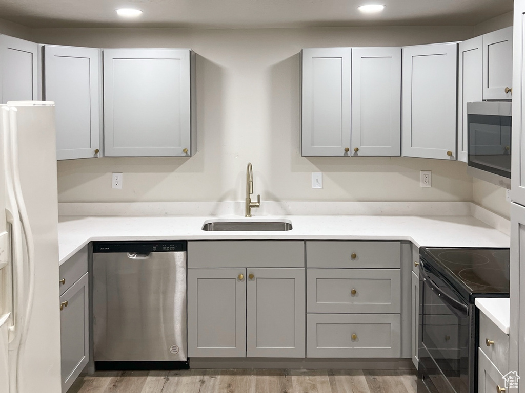 Kitchen featuring stainless steel appliances, a sink, gray cabinets, light wood finished floors, and recessed lighting