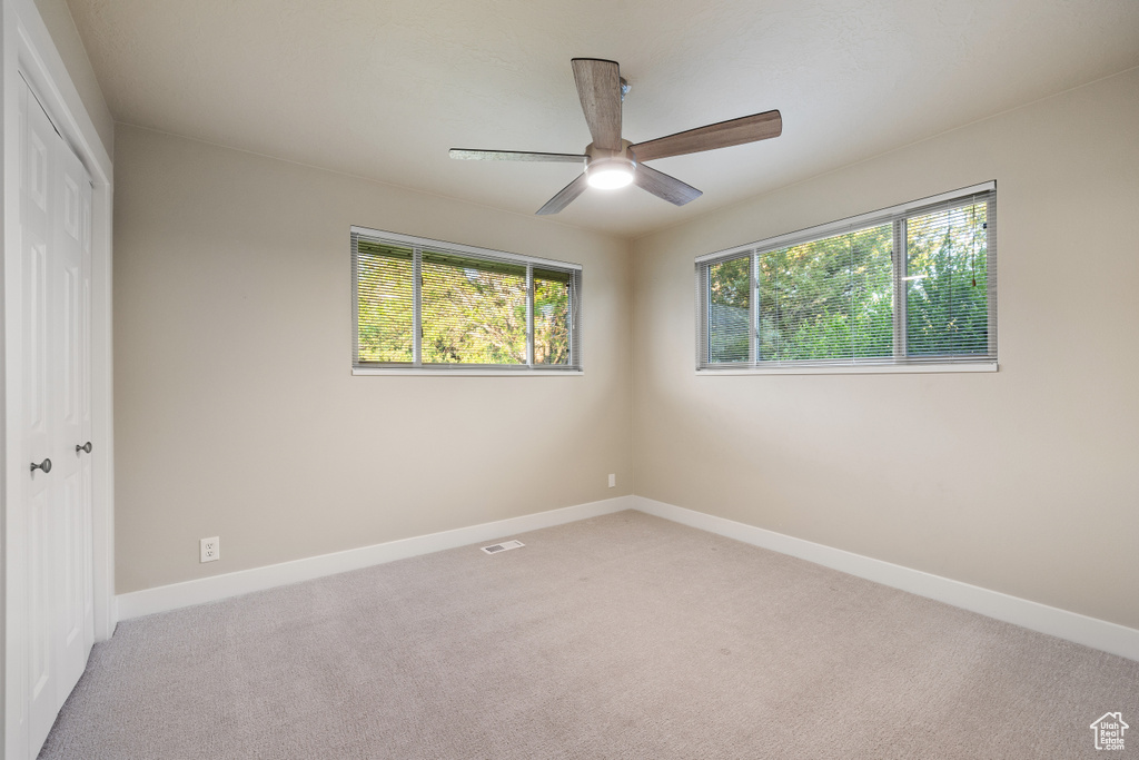 Unfurnished bedroom with light colored carpet, a closet, baseboards, and ceiling fan