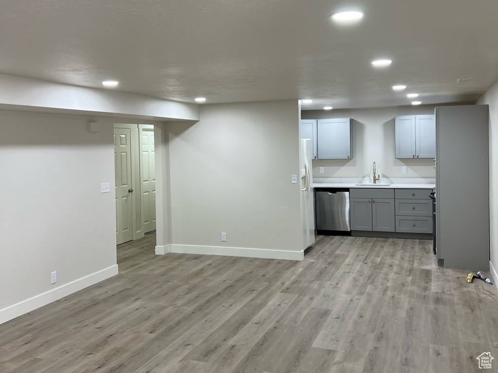 Unfurnished living room featuring a sink, recessed lighting, baseboards, light wood-style floors, and a textured ceiling