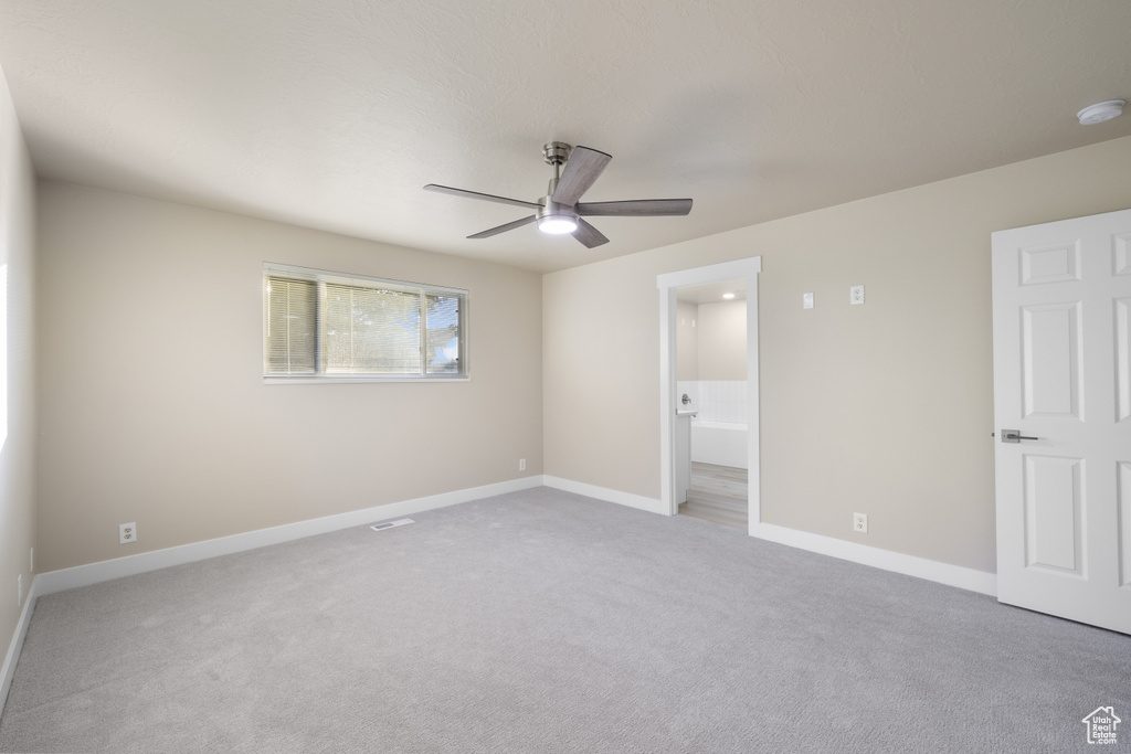 Unfurnished bedroom featuring carpet floors, baseboards, ensuite bath, and ceiling fan