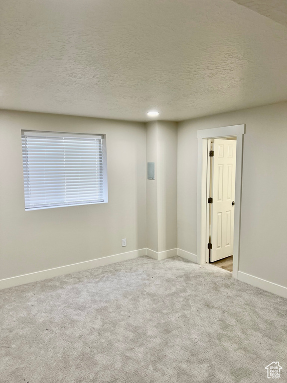 Carpeted spare room with baseboards and a textured ceiling