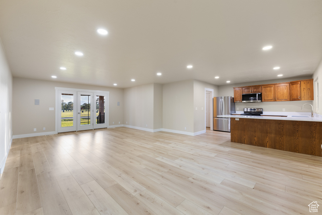 Kitchen featuring stainless steel appliances, recessed lighting, open floor plan, light countertops, and a sink