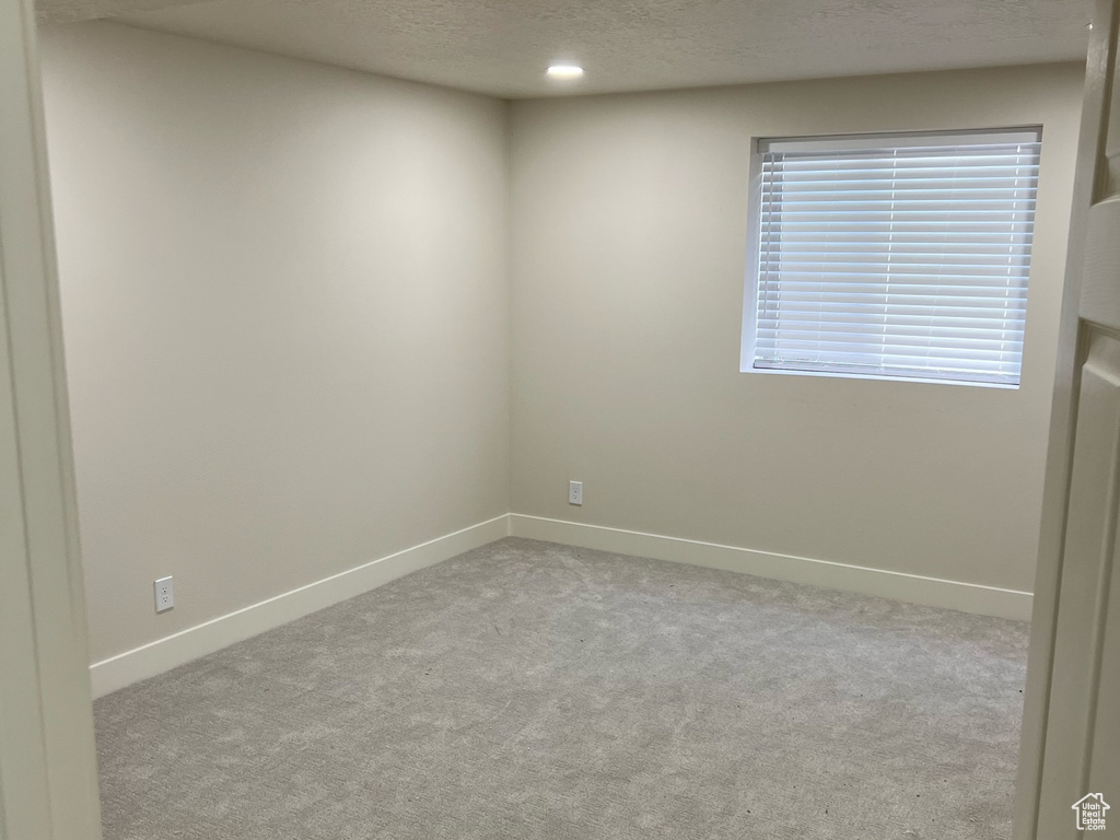 Carpeted spare room with a textured ceiling and baseboards