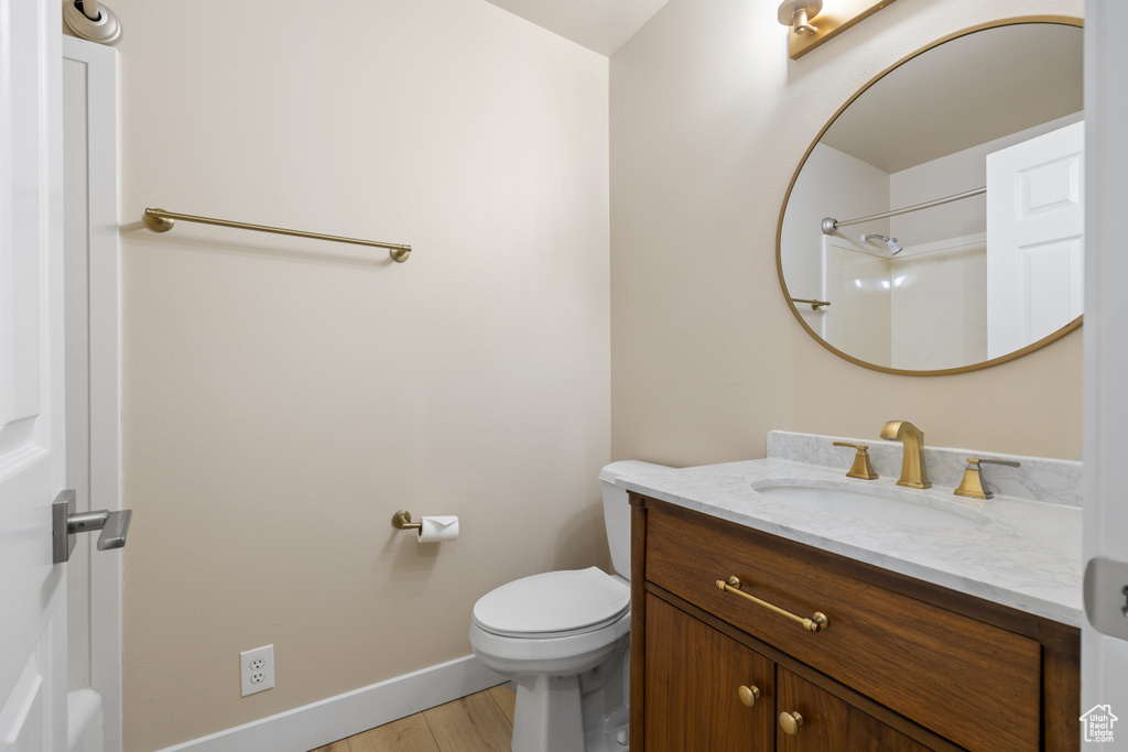 Full bathroom with vanity, baseboards, toilet, and wood finished floors