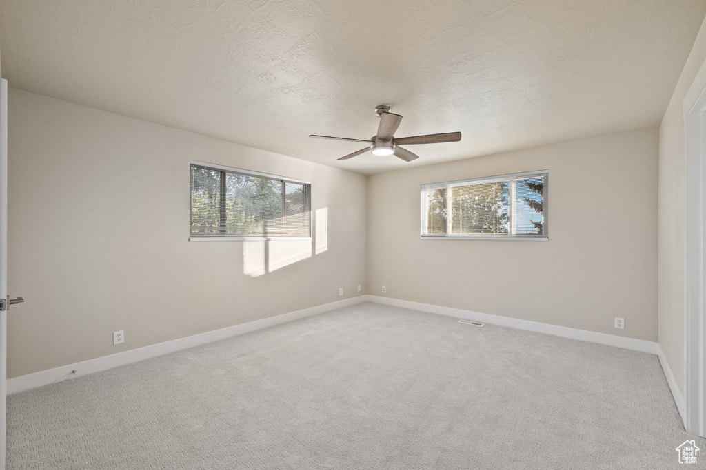 Unfurnished room with a ceiling fan, light colored carpet, and baseboards