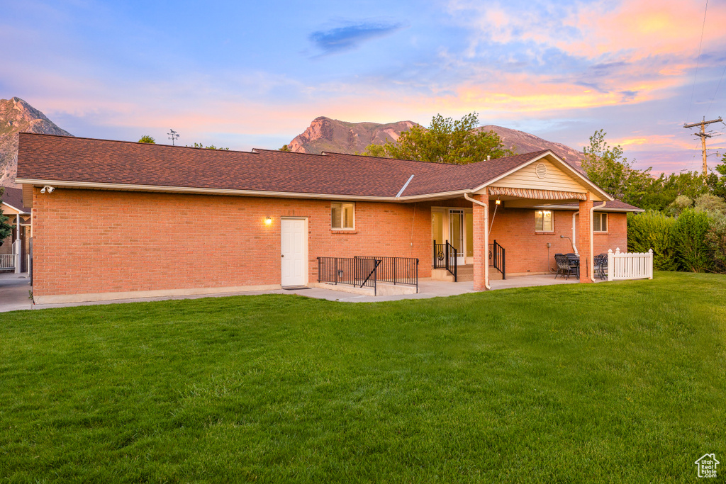 Back of property at dusk featuring a patio, brick siding, a mountain view, and entry steps