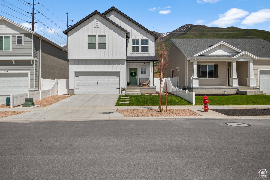 View of front of property with board and batten siding, concrete driveway, an attached garage, and covered porch