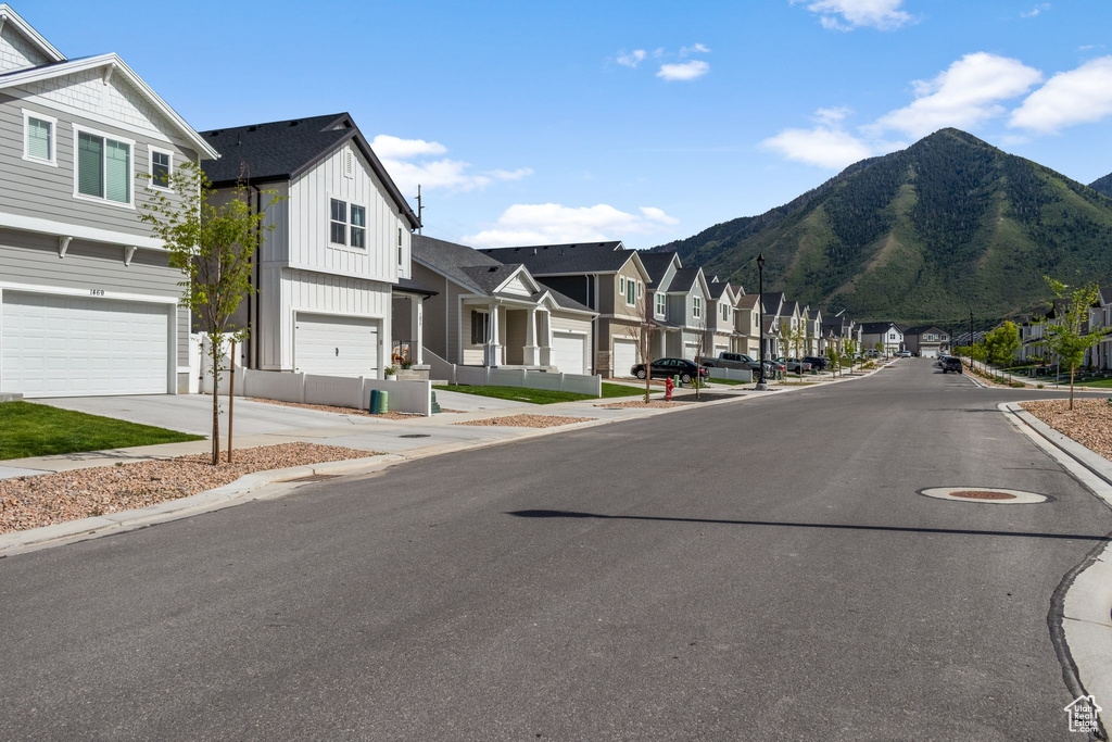 View of asphalt street with a residential view, a mountain view, sidewalks, and curbs