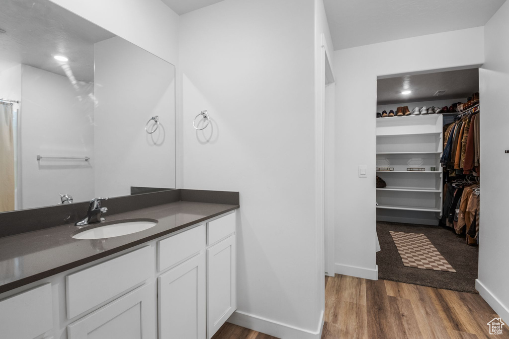 Full bathroom featuring vanity, a spacious closet, wood finished floors, and baseboards
