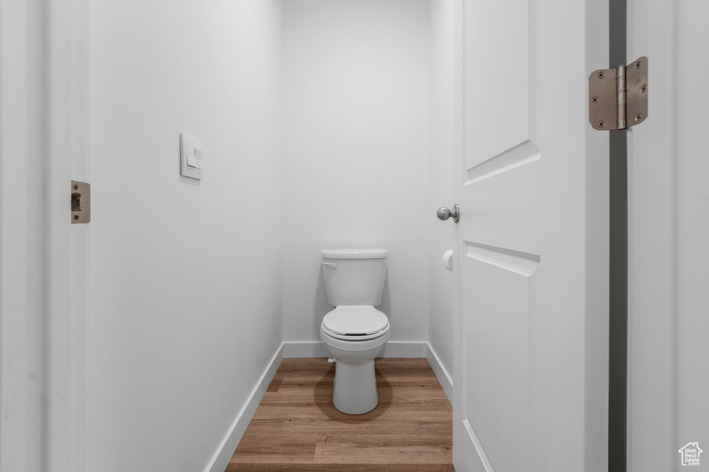Bathroom with toilet, wood finished floors, and baseboards