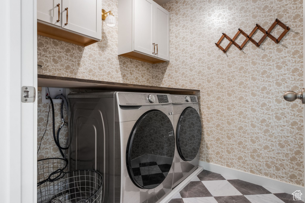 Laundry area featuring washing machine and clothes dryer, cabinet space, and baseboards