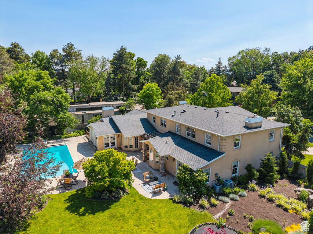 View from above of property with a pool and a tree filled landscape