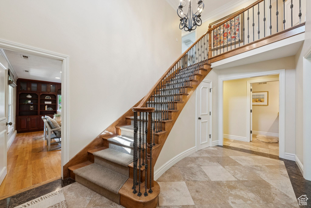 Staircase featuring a high ceiling, a chandelier, and baseboards