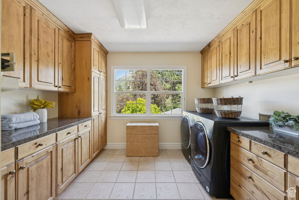 Washroom with cabinet space, baseboards, and washer and clothes dryer