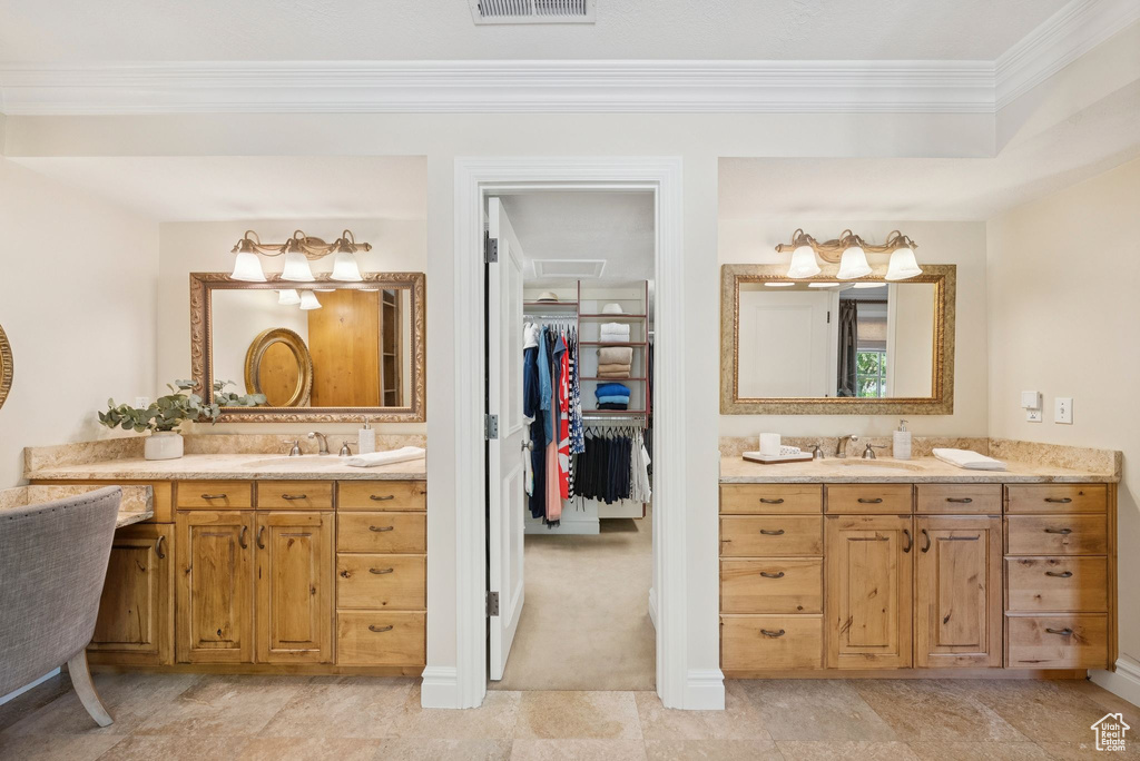 Bathroom featuring crown molding, two vanities, baseboards, and a walk in closet