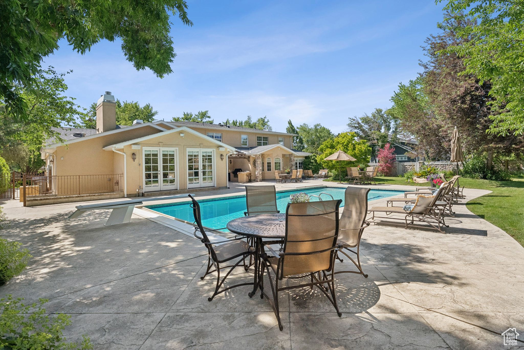 Outdoor pool with french doors, a patio area, and a diving board