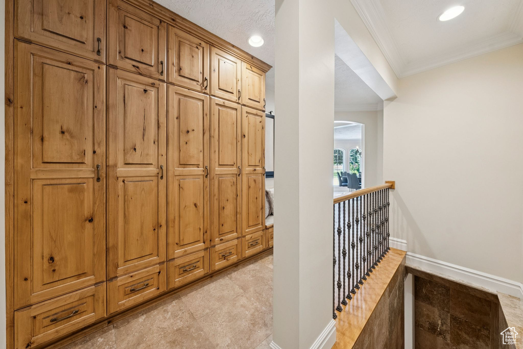 Hall with ornamental molding, baseboards, an upstairs landing, arched walkways, and recessed lighting