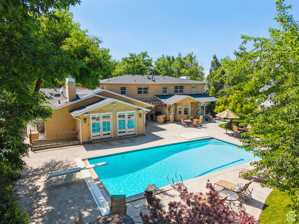 Outdoor pool featuring a patio, french doors, and a diving board