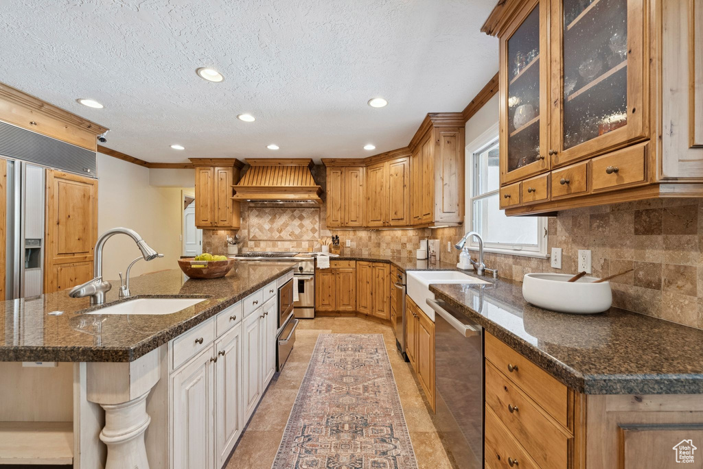 Kitchen featuring custom range hood, stainless steel appliances, a sink, tasteful backsplash, and recessed lighting