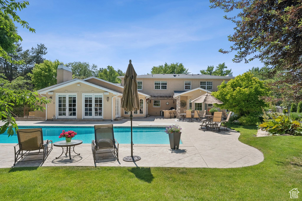 Outdoor pool featuring french doors, a lawn, and a patio area