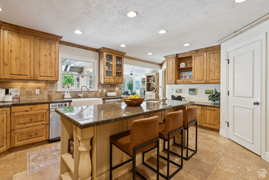 Kitchen featuring open shelves, stainless steel dishwasher, crown molding, a breakfast bar, and decorative backsplash