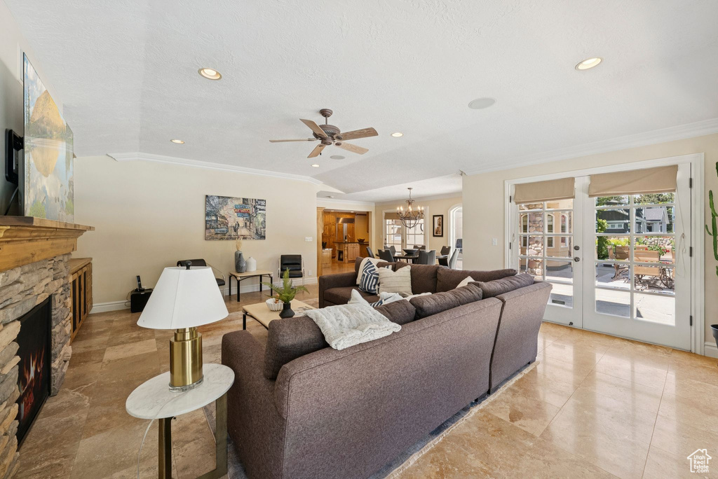 Living room featuring a chandelier, healthy amount of natural light, ornamental molding, a fireplace, and a ceiling fan